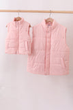 Two pink puffer vests hanging on a rack against a white background