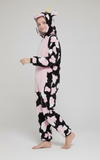 Person wearing a cow-themed onesie with pink hearts on a white background