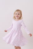 Young girl wearing a pink dress with a subtle pattern on a white background